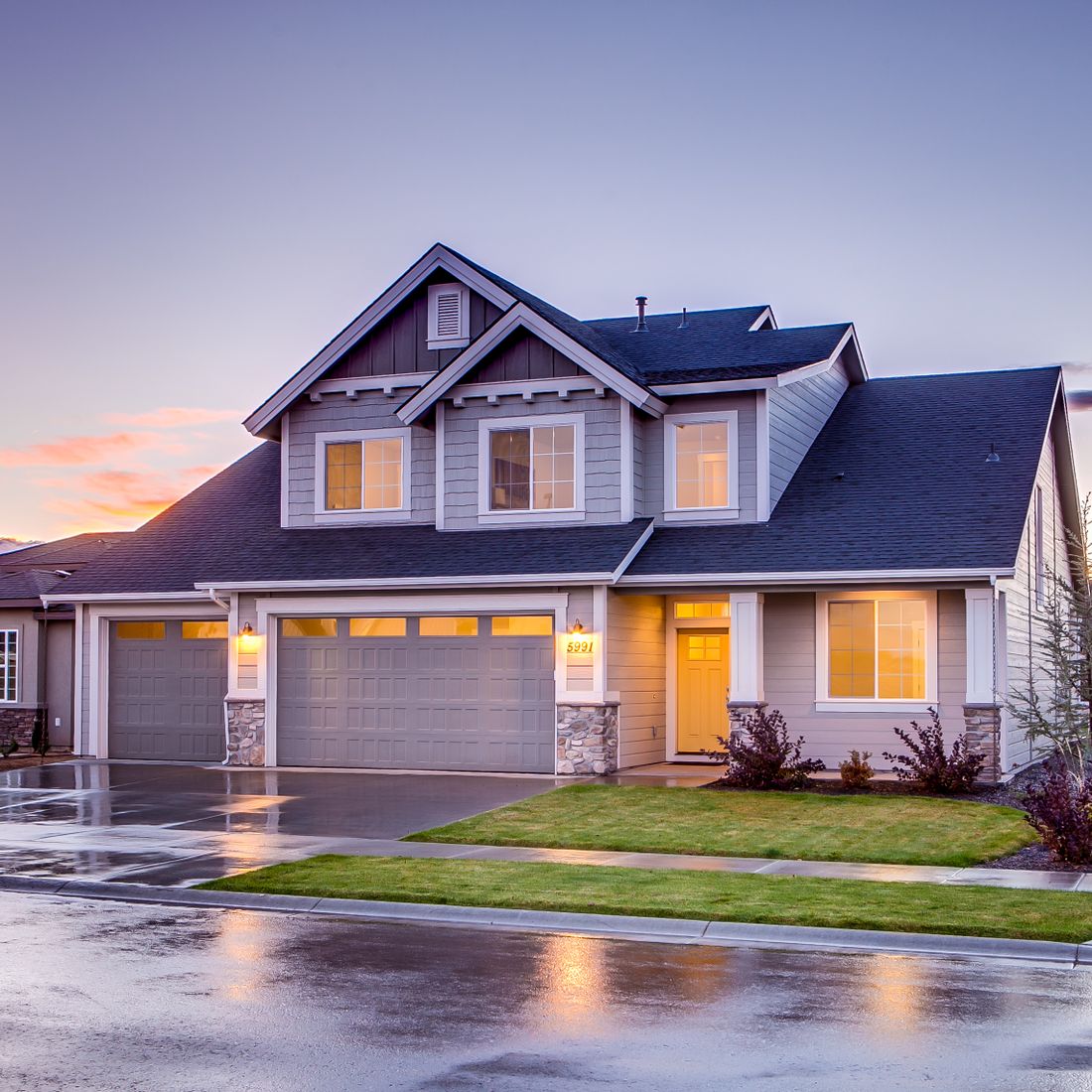 Residential home at dusk with lit windows